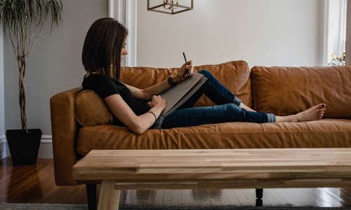 a person laying on a couch writing